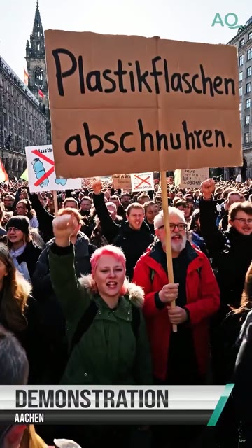 Standbild: Demonstration mit Protestschild, darunter eine Bauchbinde im Nachrichten-Look.