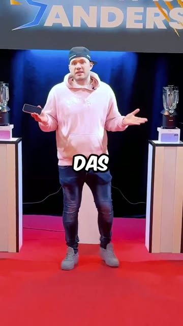 Standbild: Mann auf einer Bühne, darüber eine große animierte Wort-Einblendung.